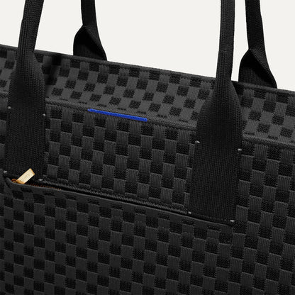 A closeup of The Classic Tote in Black Sand, focusing on the exterior zip pocket.