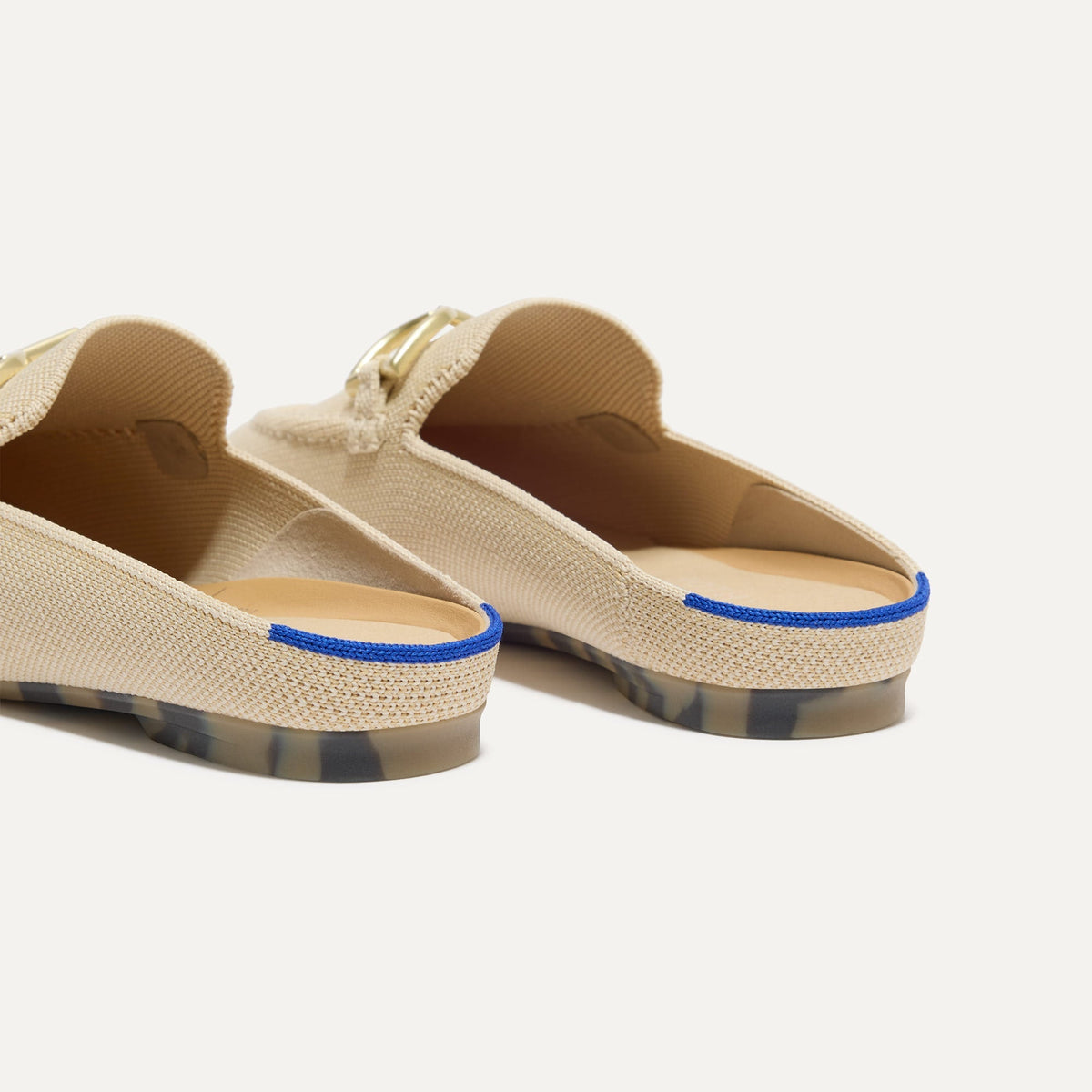 Close up of the heel of The Double Bit Loafer Mule in Sandstone, with Rothy's signature blue halo.