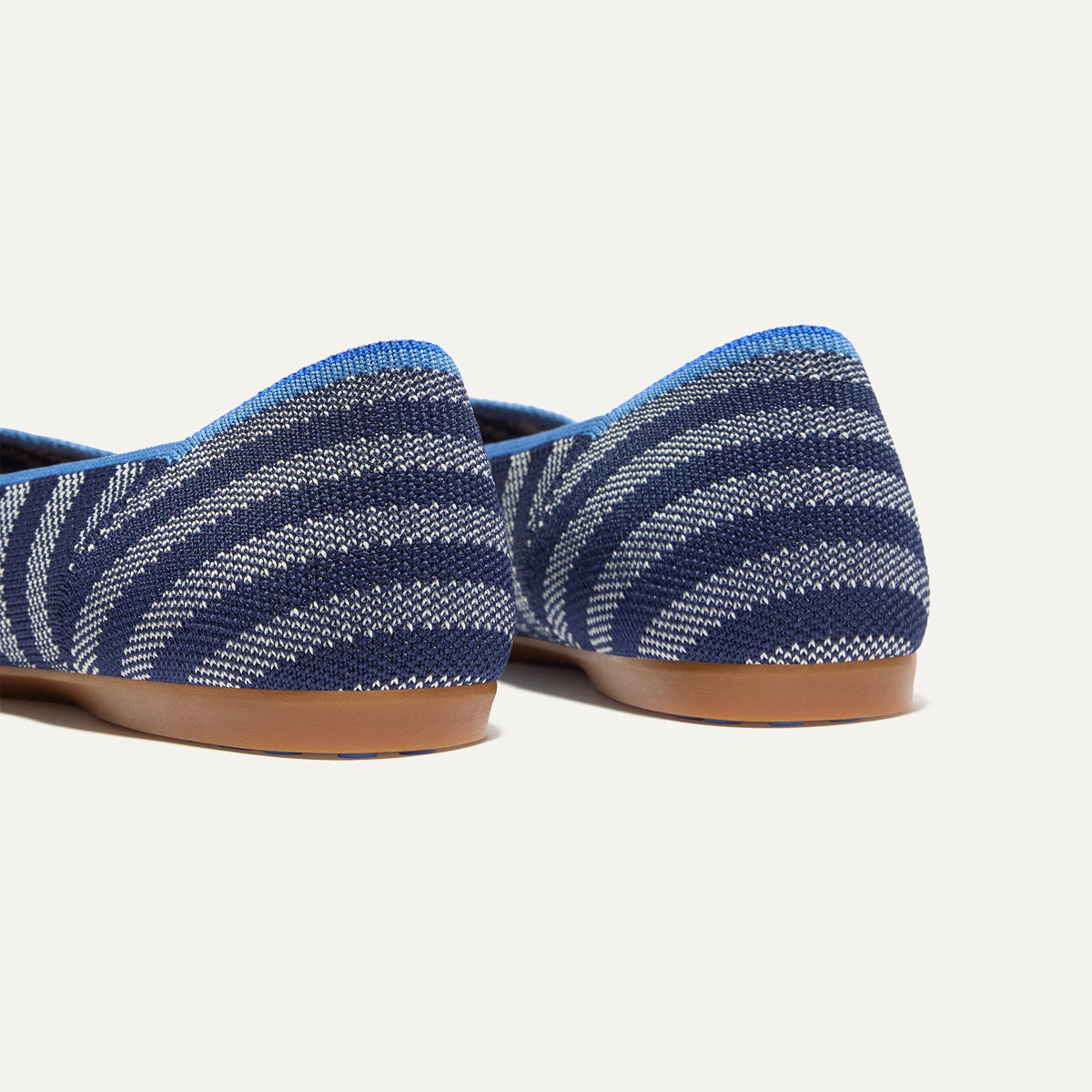 Close up of the heel of The Daily Flat in Harbor Cabana Stripe, with Rothy's signature blue halo.