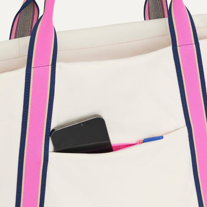 A close up of The Travel Tote in Optic with a phone slipped into the outer pocket.