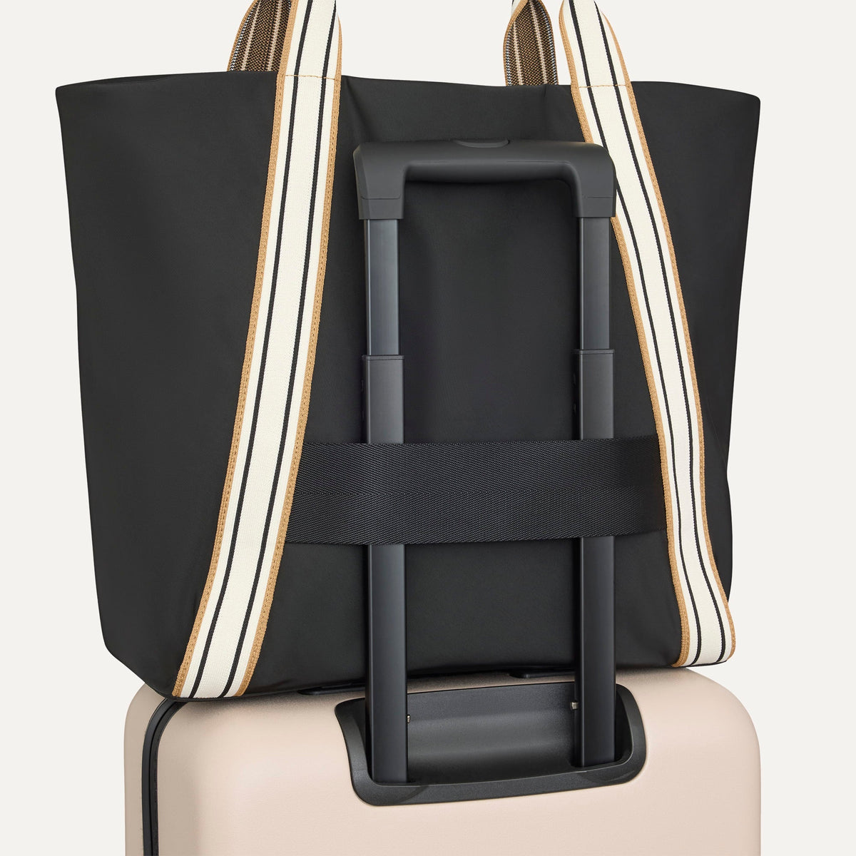 The Travel Tote in Ink, shown attached to a rolling suitcase using the wrap-around band.