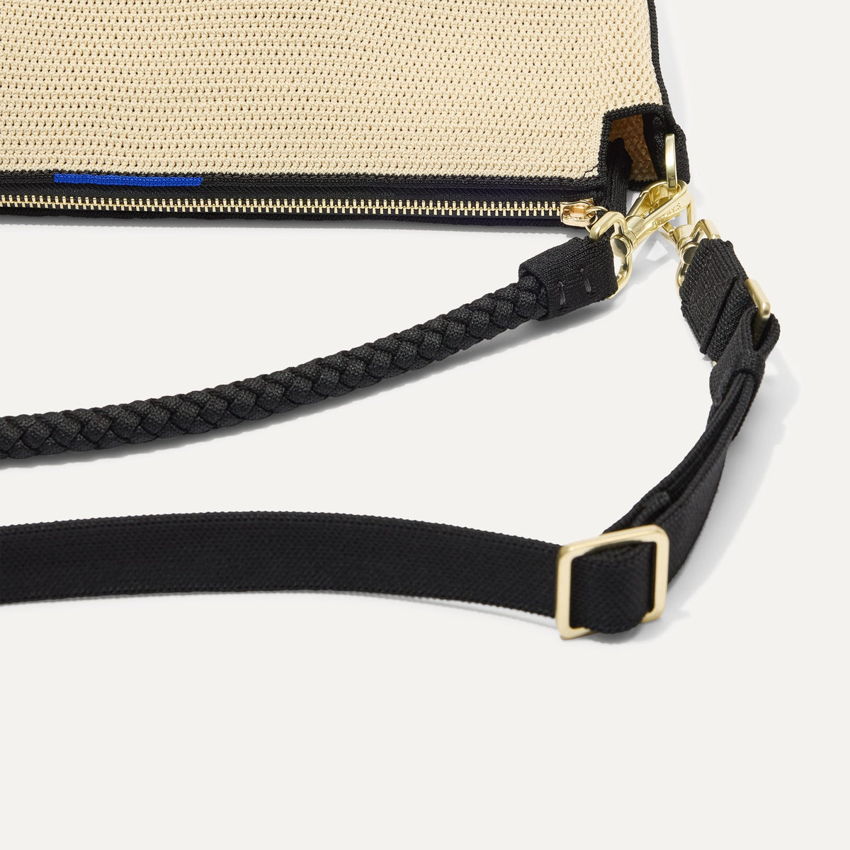The Daily Crossbody in Black and White Raffia-Knit, lying flat, showing the detachable top handle and adjustable crossbody strap.